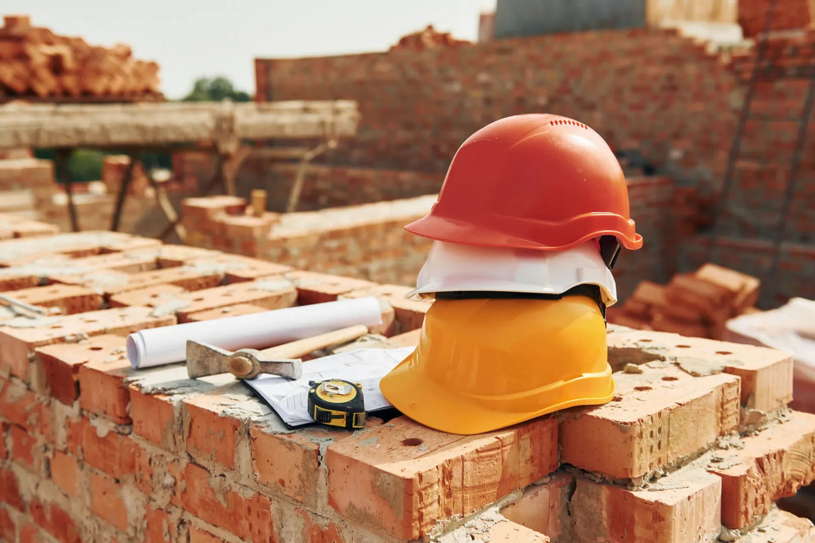 Construction tools and safety helmets on brick wall.