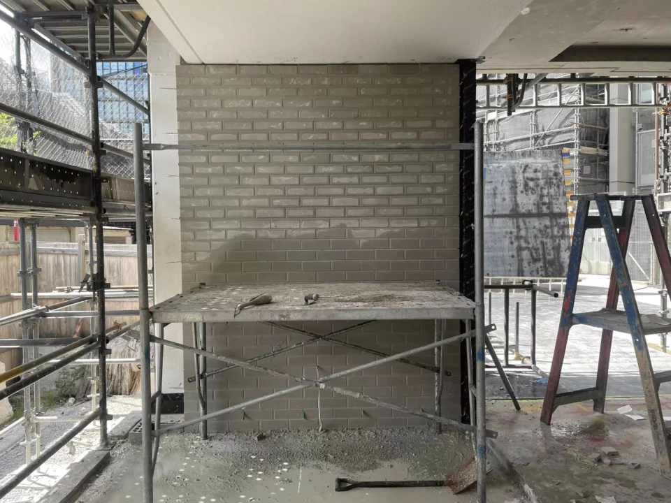 Brick wall construction site with scaffolding and ladder.