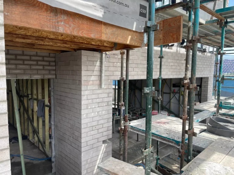 Brick building construction with scaffolding and exposed frames.
